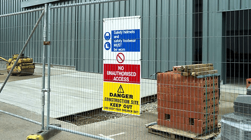 Construction site safety sign behind a fence