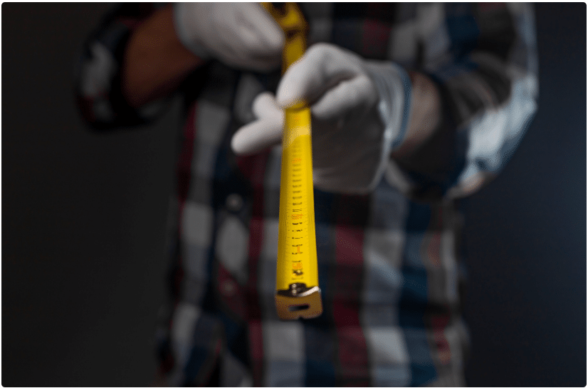 Worker wearing protective gloves holding a yellow measuring tape
