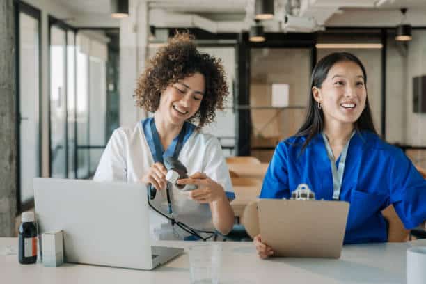 Nurses using laptop together at desk
